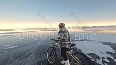 女人在冰上骑自行车。 女孩穿着银色<strong>羽绒服</strong>，自行车背包和头盔。 女人是